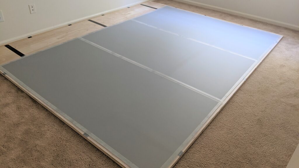 three grey marley panels have been taped on top of the wood | dance floor on carpet step 3
