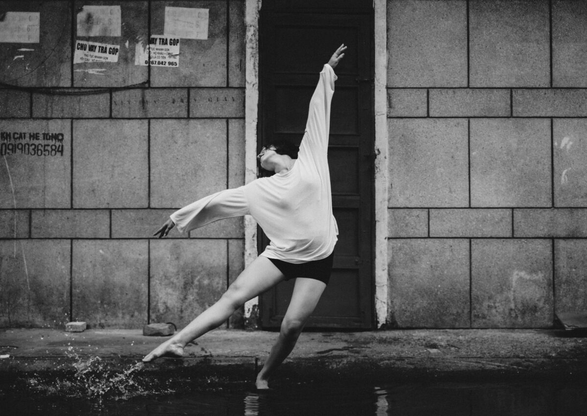 black and white photo of young woman dancing in front of old building | Dance Insight, Most Common Tricks at Professional Dance Auditions