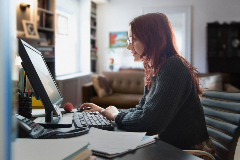 young woman with red hair and glasses working at a home computer | Dance Insight | 10 Things Pro Dancers Should Do Before Moving to a New City