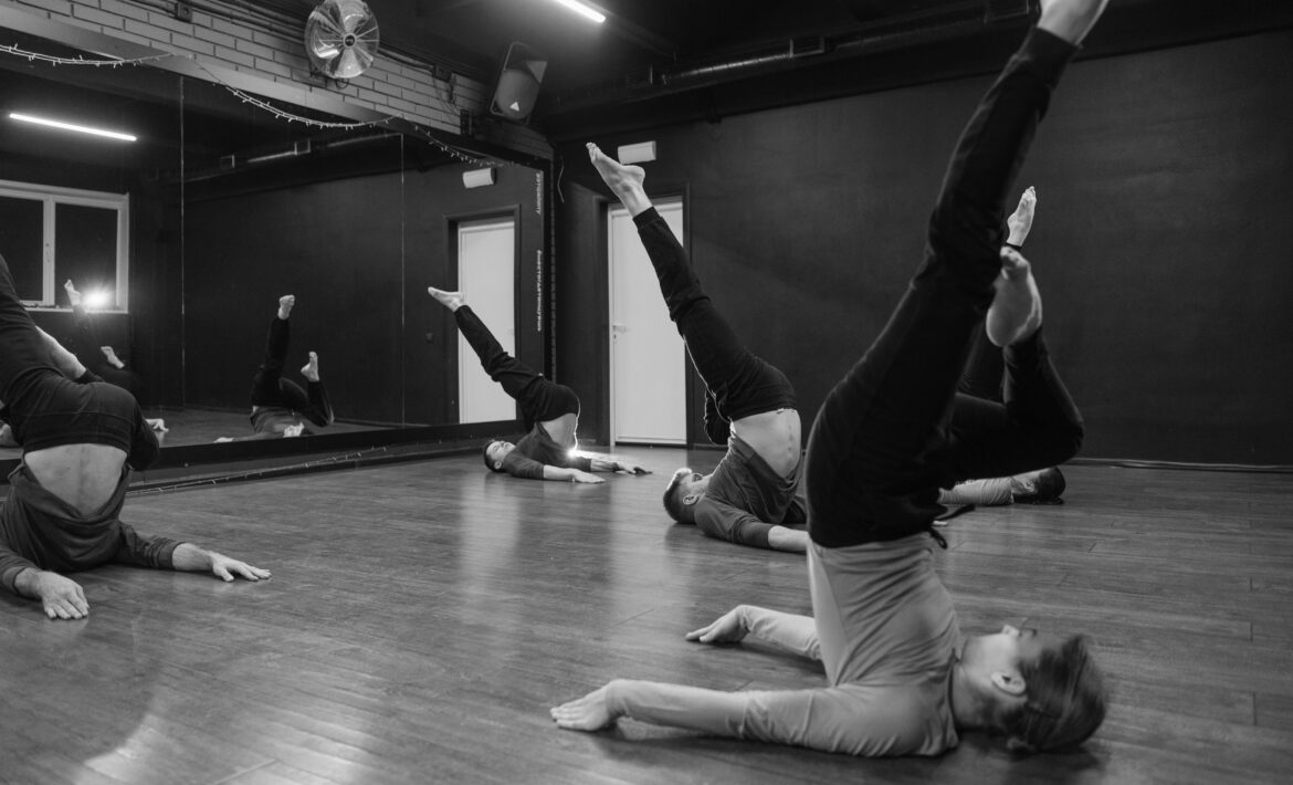 Black and white photo of 5 dancers in a candlestick pose with legs in the air | Dance Insight