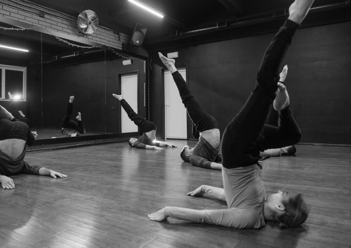Black and white photo of 5 dancers in a candlestick pose with legs in the air | Dance Insight