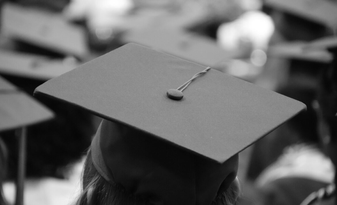 black and white photo of a person wearing a graduation cap, from behind