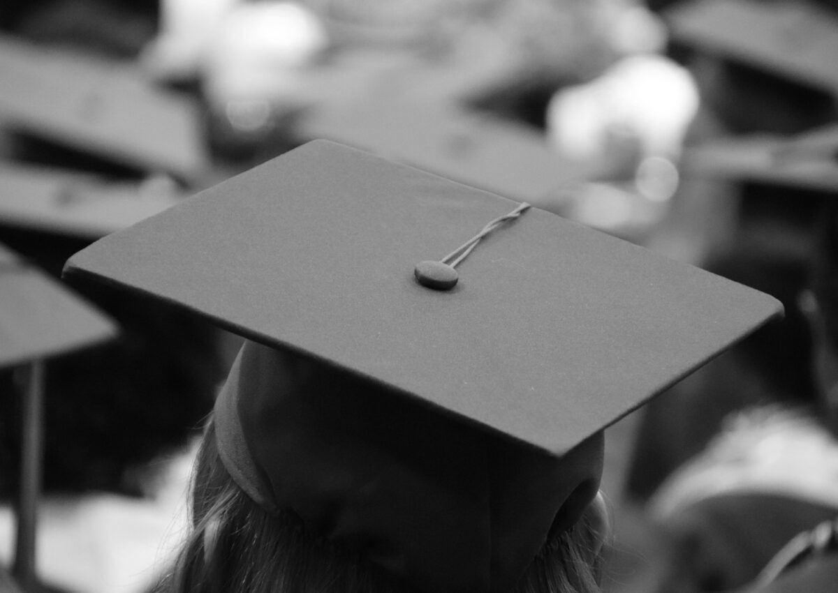 black and white photo of a person wearing a graduation cap, from behind